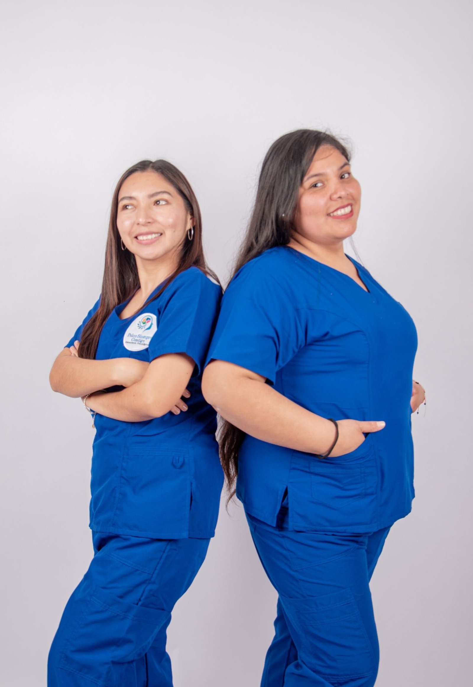 Dos enfermeras latinas sonriendo en uniforme azul
